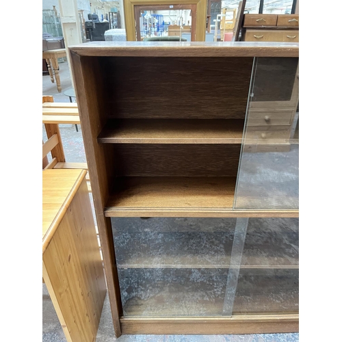 1034 - A Herbert Gibbs teak bookcase with four glass sliding doors - approx. 113cm high x 91cm wide x 24cm ... 