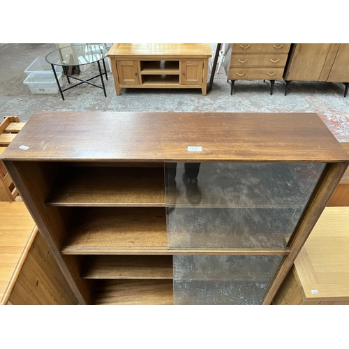 1034 - A Herbert Gibbs teak bookcase with four glass sliding doors - approx. 113cm high x 91cm wide x 24cm ... 