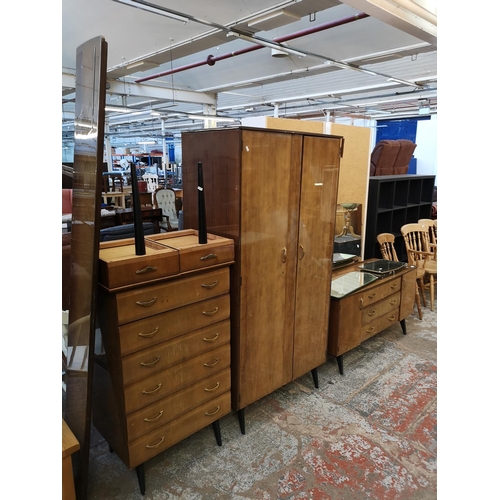 1052 - A mid 20th century walnut effect four piece bedroom suite comprising dressing table, double wardrobe... 