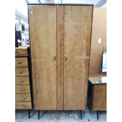 1052 - A mid 20th century walnut effect four piece bedroom suite comprising dressing table, double wardrobe... 