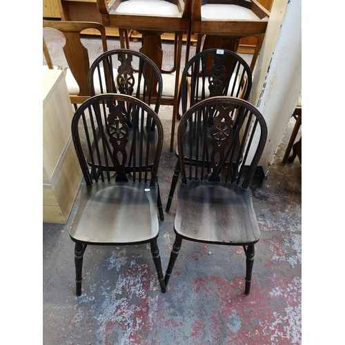 1064 - A set of four stained beech wheelback dining chairs