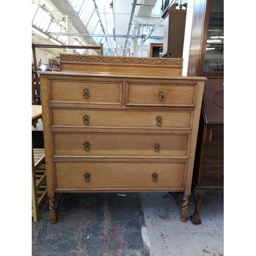 1106 - An early 20th century oak chest of two short over three long drawers with carved gallery back and ba... 