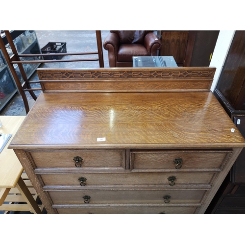 1106 - An early 20th century oak chest of two short over three long drawers with carved gallery back and ba... 