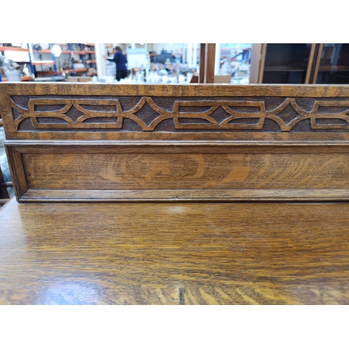 1106 - An early 20th century oak chest of two short over three long drawers with carved gallery back and ba... 