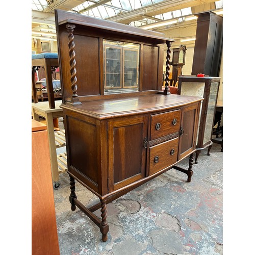 1120 - An early 20th century oak mirror back sideboard with barley twist design, two central drawers and tw... 