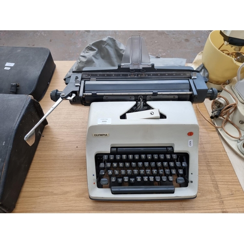 1553 - An Olympia International desktop typewriter with cover and boxed spare ribbon