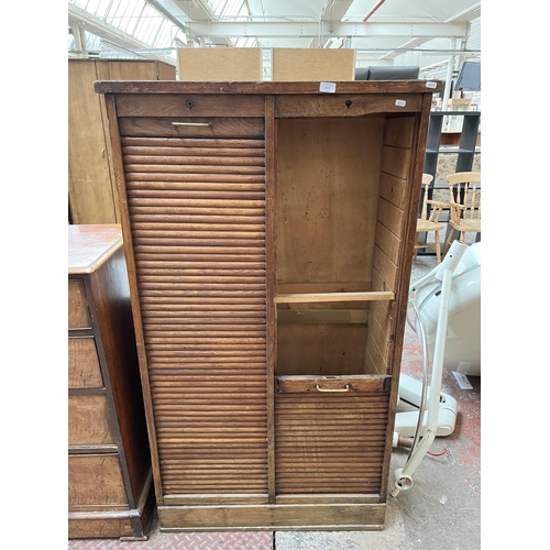 28 - An early 20th century oak double tambour door cabinet - approx. 152cm high x 87cm wide x 37cm deep