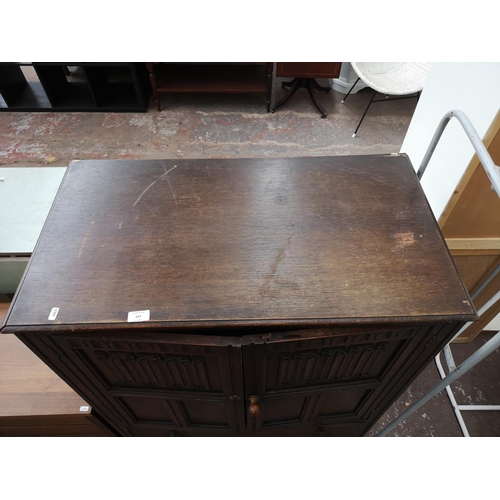 107 - An oak linen fold cabinet with two doors and two lower drawers