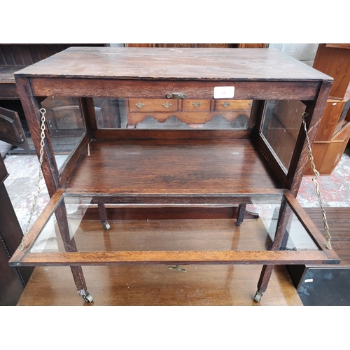 12 - An early 20th century oak and glass bijouterie table - approx. 70cm high x 59cm wide x 34cm deep