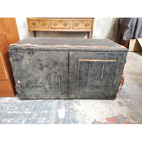 23 - An early 20th century pine travel trunk converted two door cabinet