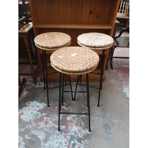 34 - Three mid 20th century wicker and black metal kitchen bar stools - approx. 74cm high x 33cm diameter