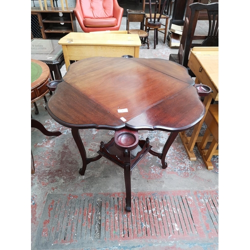 40 - An Edwardian mahogany quatrefoil folding two tier games table - approx. 69cm high x 45cm wide