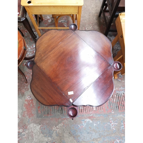 40 - An Edwardian mahogany quatrefoil folding two tier games table - approx. 69cm high x 45cm wide