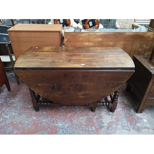 53 - A 17th century style solid oak bobbin turned drop leaf gate leg dining table - approx. 74cm high x 1... 