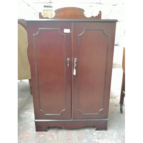 72 - Three pieces of mahogany furniture, two mid 20th century two tier tea trolleys and one two door medi... 