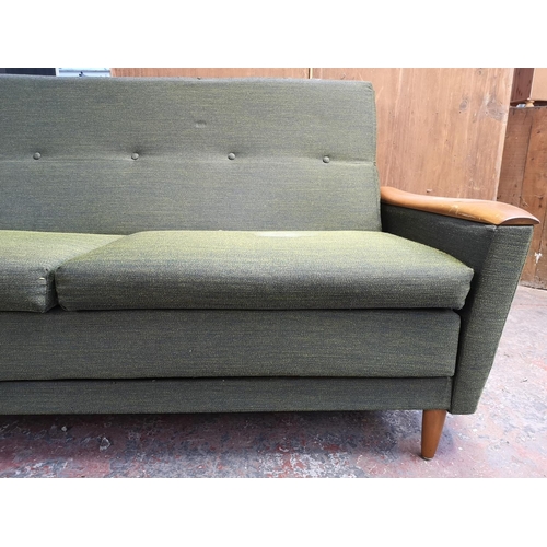 131 - A mid 20th century Greaves & Thomas green upholstered and teak two seater sofa bed