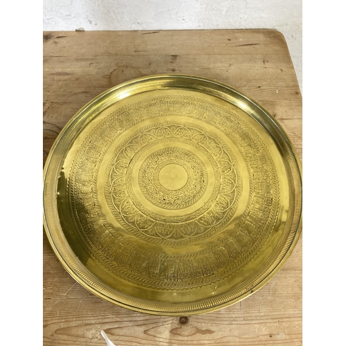 444 - Three items, two brass circular trays - approx. 58cm in diameter and one wooden folding travel table