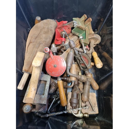 233 - A collection of assorted tools to include two cast iron bench vices, hand drills, wood plane etc.