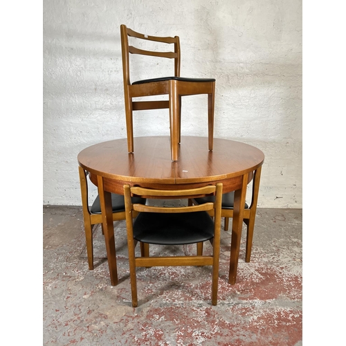 32 - A mid 20th century teak extending circular dining table and four beech and black vinyl dining chairs