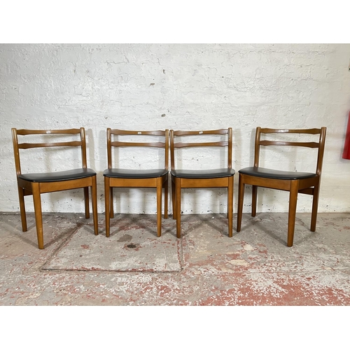 32 - A mid 20th century teak extending circular dining table and four beech and black vinyl dining chairs