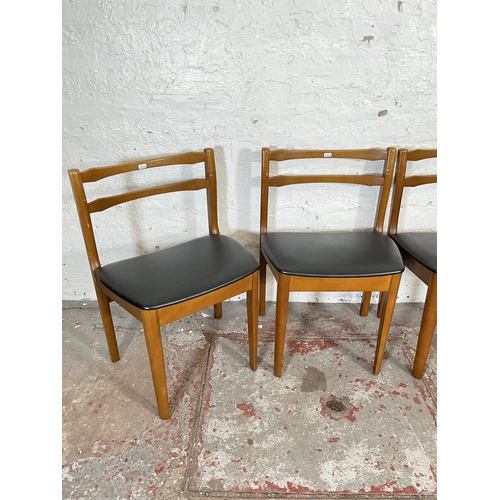 32 - A mid 20th century teak extending circular dining table and four beech and black vinyl dining chairs