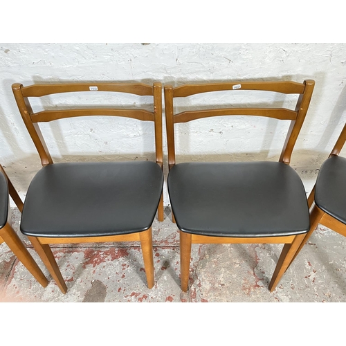 32 - A mid 20th century teak extending circular dining table and four beech and black vinyl dining chairs