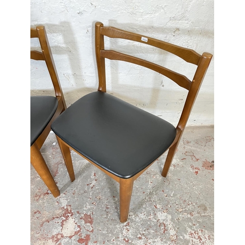 32 - A mid 20th century teak extending circular dining table and four beech and black vinyl dining chairs