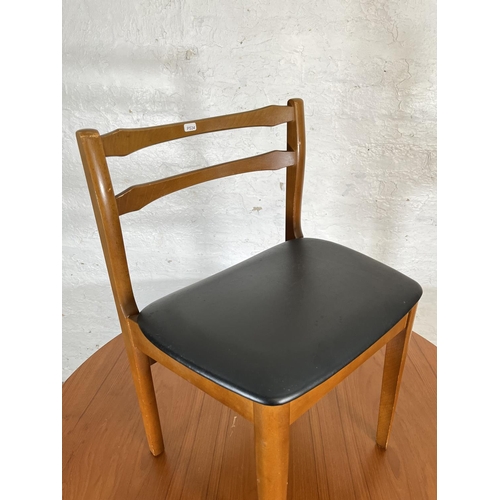 32 - A mid 20th century teak extending circular dining table and four beech and black vinyl dining chairs