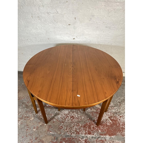 32 - A mid 20th century teak extending circular dining table and four beech and black vinyl dining chairs