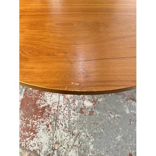 32 - A mid 20th century teak extending circular dining table and four beech and black vinyl dining chairs