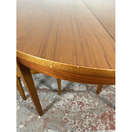 32 - A mid 20th century teak extending circular dining table and four beech and black vinyl dining chairs