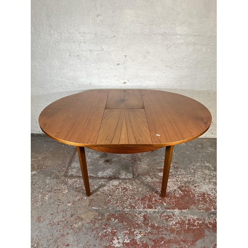 32 - A mid 20th century teak extending circular dining table and four beech and black vinyl dining chairs