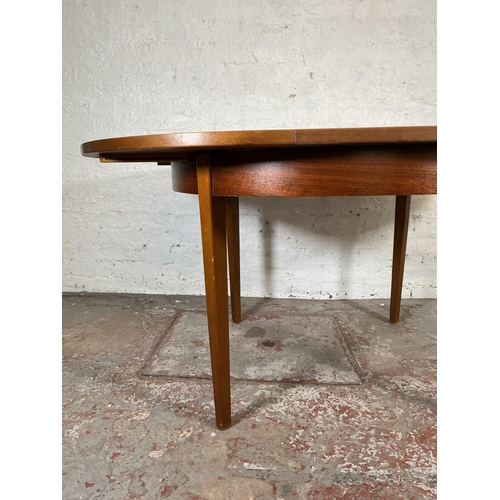 32 - A mid 20th century teak extending circular dining table and four beech and black vinyl dining chairs