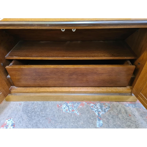 115 - An oak TV stand with two cupboard doors and fitted interior - approx. 55cm high x 95cm wide x 46cm d... 