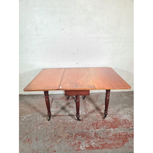 14 - A Victorian mahogany drop leaf gate leg dining table with original brass castors - approx. 74cm high... 