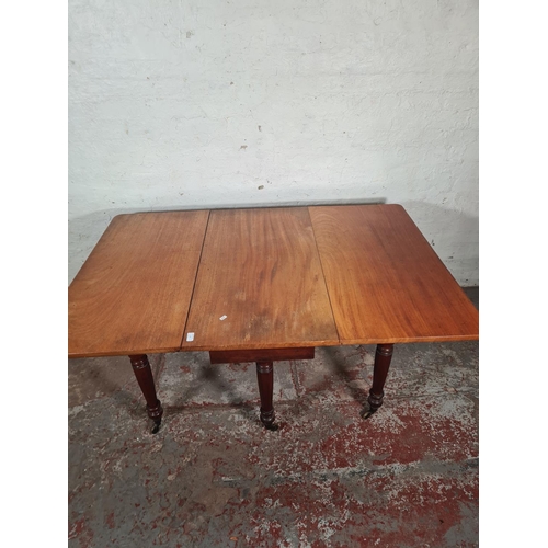 14 - A Victorian mahogany drop leaf gate leg dining table with original brass castors - approx. 74cm high... 