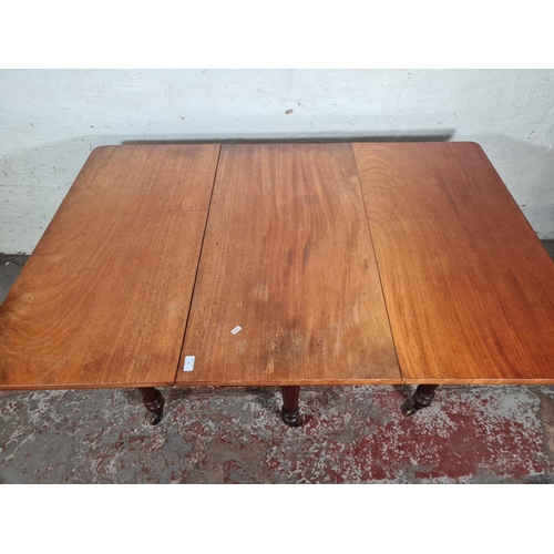 14 - A Victorian mahogany drop leaf gate leg dining table with original brass castors - approx. 74cm high... 