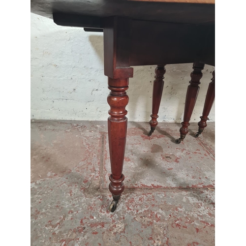 14 - A Victorian mahogany drop leaf gate leg dining table with original brass castors - approx. 74cm high... 