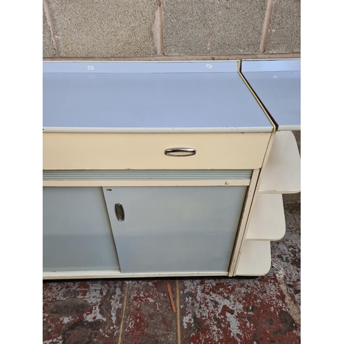 146 - A 1950s pale blue and white laminate kitchen cabinet with foldout side table, two sliding doors and ... 