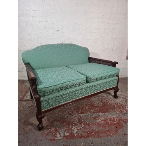 2 - An early 20th century mahogany and rattan bergere sofa with green upholstery and ball and claw suppo... 