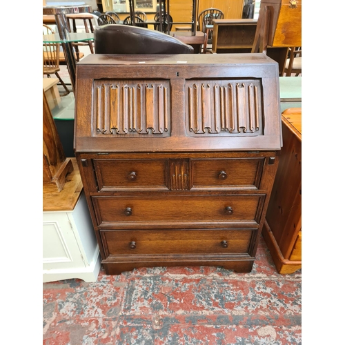 73 - An oak linenfold bureau with three drawers and fall front - approx. 100cm high x 76cm wide x 43cm de... 