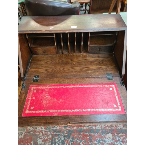 73 - An oak linenfold bureau with three drawers and fall front - approx. 100cm high x 76cm wide x 43cm de... 