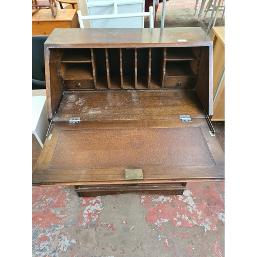 79 - A mid 20th century oak bureau with carved fall front and three drawers