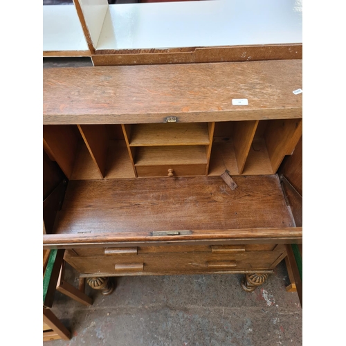 82 - A 1930s oak bureau with carved baluster supports, two drawers and fall front