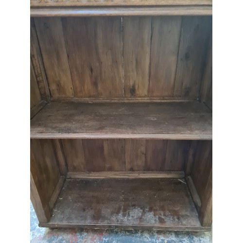 148B - A carved oak two tier free standing open bookcase - approx. 82cm high x 67cm wide x 28cm deep