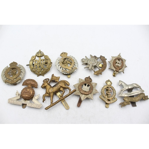 1185 - Ten military cap badges to include The Lancashire Fusiliers, The Devonshire Regiment etc.