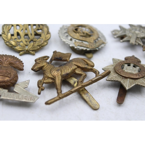 1185 - Ten military cap badges to include The Lancashire Fusiliers, The Devonshire Regiment etc.