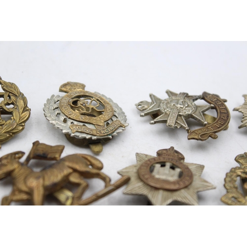 1185 - Ten military cap badges to include The Lancashire Fusiliers, The Devonshire Regiment etc.