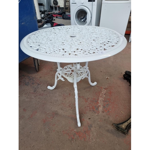 647 - A Victorian style cast metal circular tri-footed patio table - approx. 66cm high x 72cm diameter