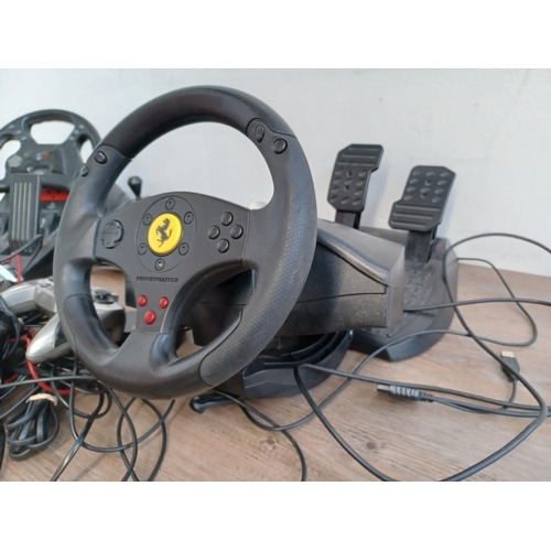 734 - A collection of gaming items to include Mad Catz steering wheel with pedals, Thrustmaster steering w... 